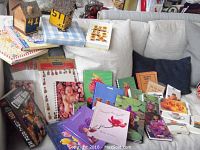 Overview of collection with multiple stationary items, cookbooks, bird houses placed on a sofa and boxes