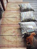 Three floral rugs laid flat on the floor with three abstract pillows and one dog embroidered pillow placed on top, showing the size and designs clearly.