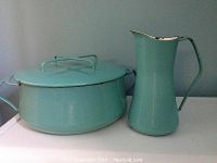 Photo of turquoise enamel covered pot and pitcher side by side on a surface, showing color and shape of two pieces.