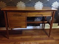 Full view of the mid century modern wooden desk showing front with drawer and cabinet, wood grain finish, and tapered legs