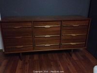 Front view of nine-drawer mid century modern dresser with visible wood grain and integrated handles.