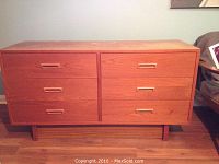 Front view of teak dresser showing six drawers with matching recessed handles and a clean wood finish.