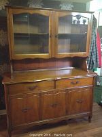 Full view of wooden Knechtel hutch with glass doors on top, wooden base with drawers and cupboards.