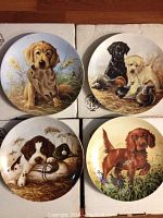 Four Bradford Exchange collector plates featuring puppies, all in original boxes, displayed on a wood surface.