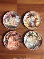 Four Bradford Exchange collector plates arranged on a wood floor showing the full set with child and pet illustrations and floral backgrounds.