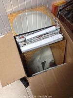 Box containing stacked vintage mirrored tiles with gold fleck borders and some newspaper between tiles.