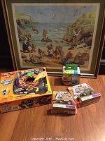 Framed print featuring teddy bears at the beach with collectible Matchbox trucks and art supplies on wood floor