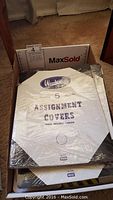 Photo showing top view of assignment covers labeled Woodlands ASSIGNMENT COVERS with assorted cover colors white, green, beige.