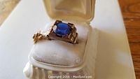 Yellow gold ring with loose blue stone shown in box