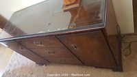 Full front view of vintage solid wood sideboard with glass top showing drawers and cabinet doors.