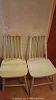 Front view of two mint colored wooden chairs showing seat and leg details.