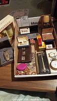 Tray overview showing wristwatch, cologne sets, cufflinks, coins, pen, beads and razor