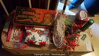 Photo of vintage Christmas decorations laid on cardboard box, including Noma Bubble-Lites box, artificial branches, silk flowers, garlands, and candle holders.
