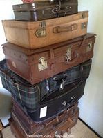 Stack of seven vintage leather and fabric suitcases of varying sizes and colors
