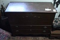 Front view of the dark wood chest showing two drawers with oval hardware and scratches on surface.