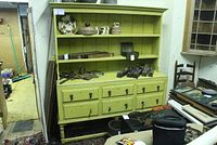 Front view of large yellow country hutch with two shelves displaying various items and six drawers below.