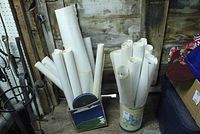 Photo of multiple rolled vintage movie posters stored upright in different containers inside a rustic wooden storage space.
