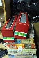 Photo showing two boxed L.G.B. train cars with red and white boxes stacked on other toy boxes.