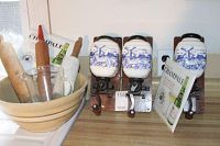 Photo of vintage kitchen items including three wall-mounted coffee grinders with blue and white ceramic jars, two ceramic mixing bowls, two wooden rolling pins, and other kitchen items on a counter.