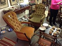 Two wood-framed upholstered chairs in olive and rust colors with a Japan tea set on a table and a bamboo fold tray table nearby.