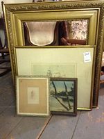 All frames and prints leaning against each other on floor with visible large ornate gold frame and three smaller framed prints.