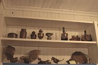 Two shelves filled with assorted decorative brass items including containers, bird figurines, candle holders, and a brass tray.