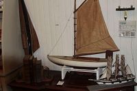 Wide shot of the nautical collectibles lot showing two sailboat models on a table.