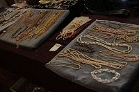 Wide view of assorted necklaces including multi-strand metallic chains and bead strands in various colors.