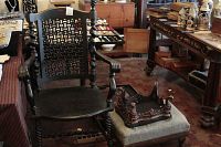 Dark carved wood armchair with twisted spindle backrest and armrests, showing signs of wear.