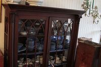 Front view of mahogany-finish china cabinet filled with dinnerware