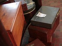 Light brown wooden box and matte gray metal box stacked with another dark wooden box beneath.