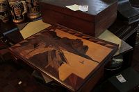 Photo showing closed rectangular wooden writing desk with a dark finish and a paper note on top.