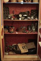 Full view of shelving unit containing various antique kitchen items including baking molds, tins, cookie cutters, sifters, and graters.