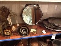 Photo of antique snuff box, small framed portraits, and decorative mirrors on a shelf, showing front views and details.