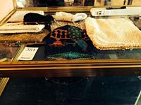 Photo showing eight small vintage evening purses, mostly beaded with various fabric and bead designs arranged on a glass shelf.