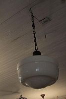 Photo of the white glass shade and black metal fixture with metal chain hanging from ceiling.