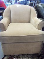 Front view of the beige upholstered armchair showing the thick detachable seat cushion and rounded armrests.