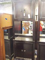 Front view of the tall dark wood cabinet, showing the mirrored middle shelf and two-door closed compartments top and bottom