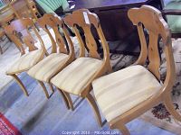 Photo showing all four wooden lyre back chairs from an angle, highlighting the upholstery and backrest design.