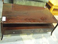 Top-down angled view of the dark wood coffee table showing glossy wood surface with some finish wear and three drawer fronts with knobs.