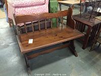 Front angle view of wooden bench showing seat, backrest with vertical spindles, and rocker legs.