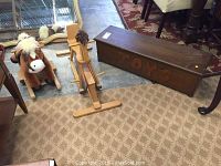 Wooden toy chest painted with the word 'TOYS' and two children's rocking horses, one plush and one wooden, shown together on a carpeted floor.