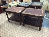 Pair of matching wooden end tables with inlaid wood tops and lower shelves, shown on a patterned carpet.