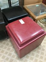 Pair of red and black square leg rests with cushioned removable tops, showing smooth leatherette upholstery and visible light wear on the red leg rest.