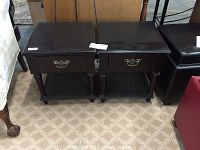 Front view of the pair of black end tables side by side, showing drawer fronts, legs, and lower shelves.