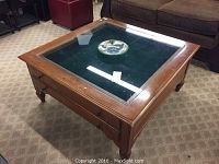 Front angle shot of the coffee table showing wooden frame, glass top, and two drawers under glass.
