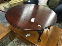 Top-down view of the round drop leaf table with dark wood surface, showing closed leafs and visible split down center and wear marks