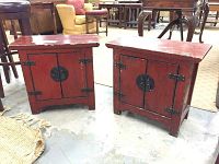 Pair of red Asian style end tables with black metal hinges and lock plates, distressed finish, front view showing doors.