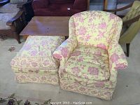 Photo showing floral patterned armchair and matching ottoman set placed on carpet with other furniture items in background