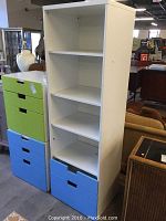 Front full view of white shelving unit with three shelves and blue drawers at base.